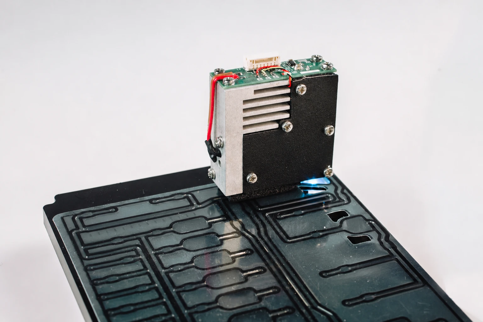 A wired prototype assembly with an exposed circuit board, finned metal features, and a channel plate.