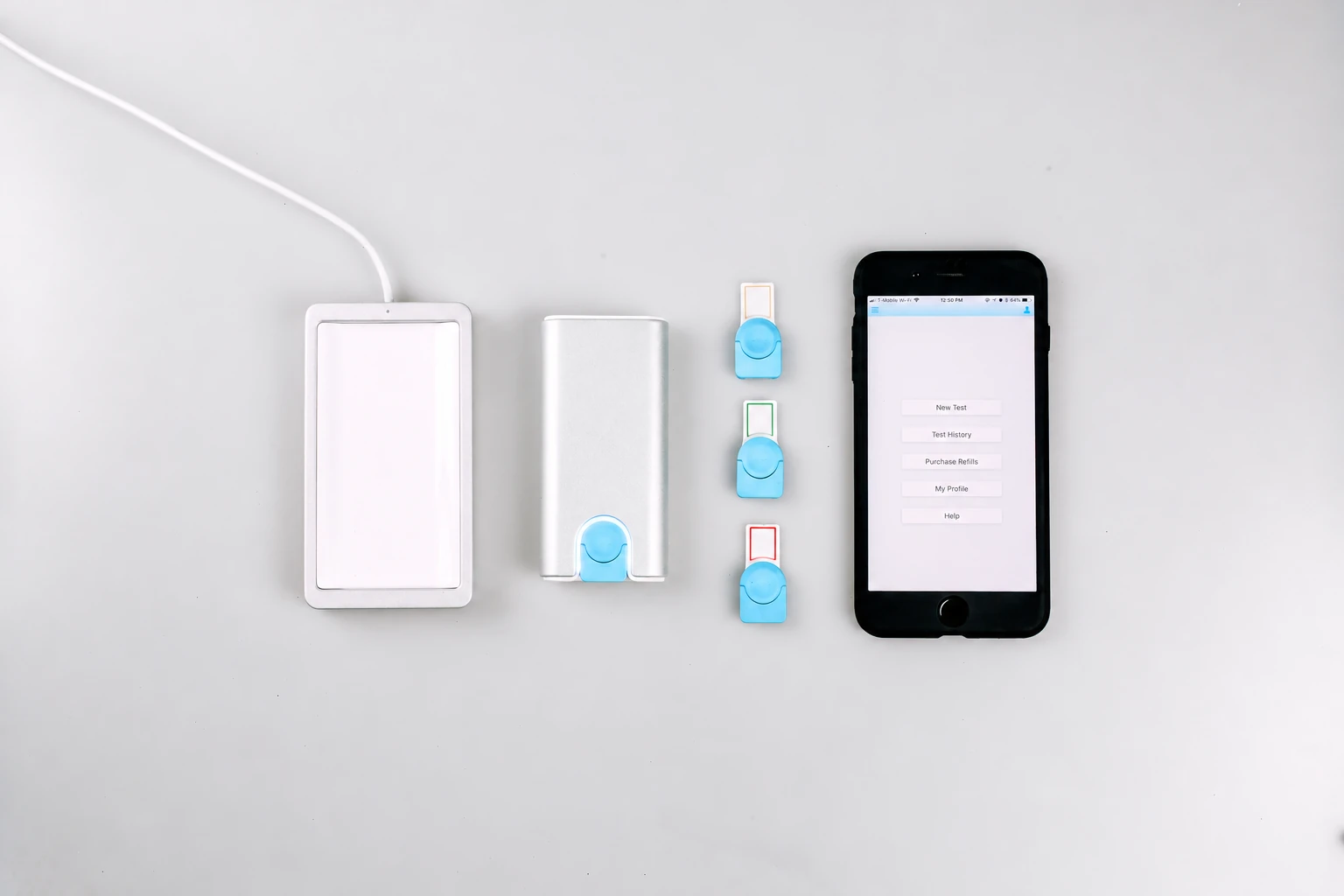 A compact reader, charging hardware, cartridges, and a smartphone interface arranged together.