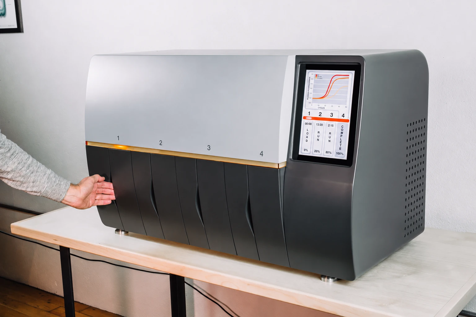 A wide laboratory instrument with loading positions and an integrated touchscreen.