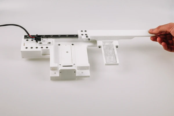 A white linear mechanism with a long lever, wiring, and visible moving interfaces.