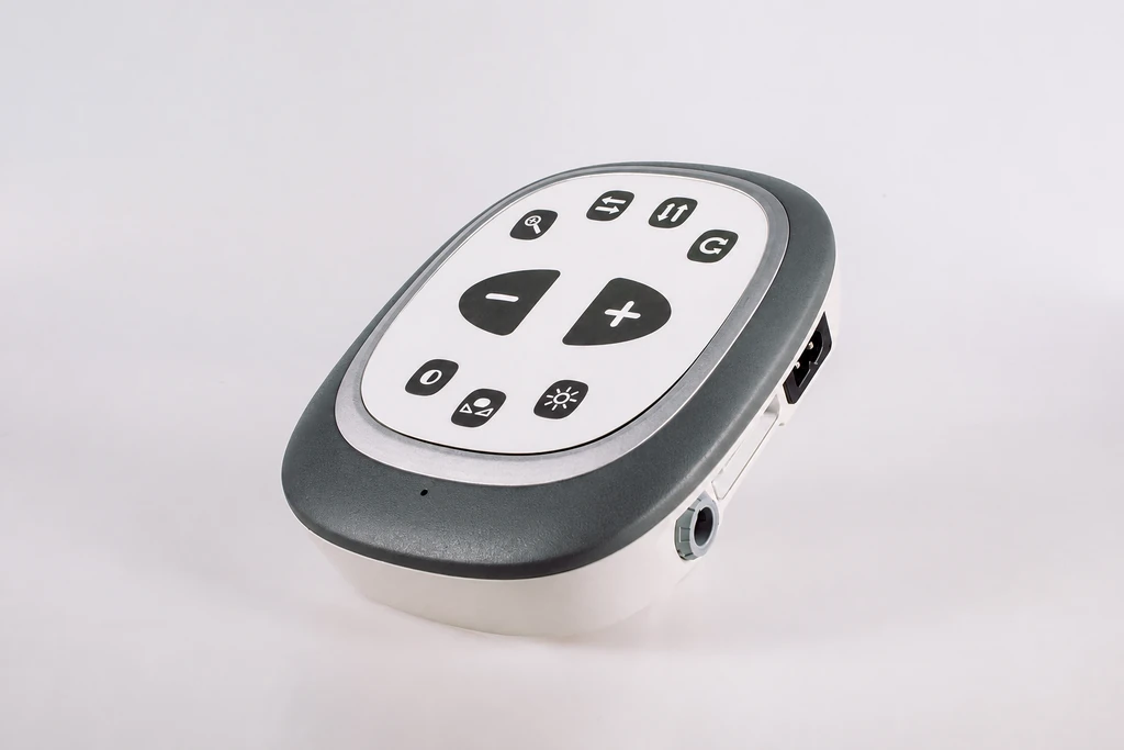 A compact handheld control interface with physical buttons and side connections.