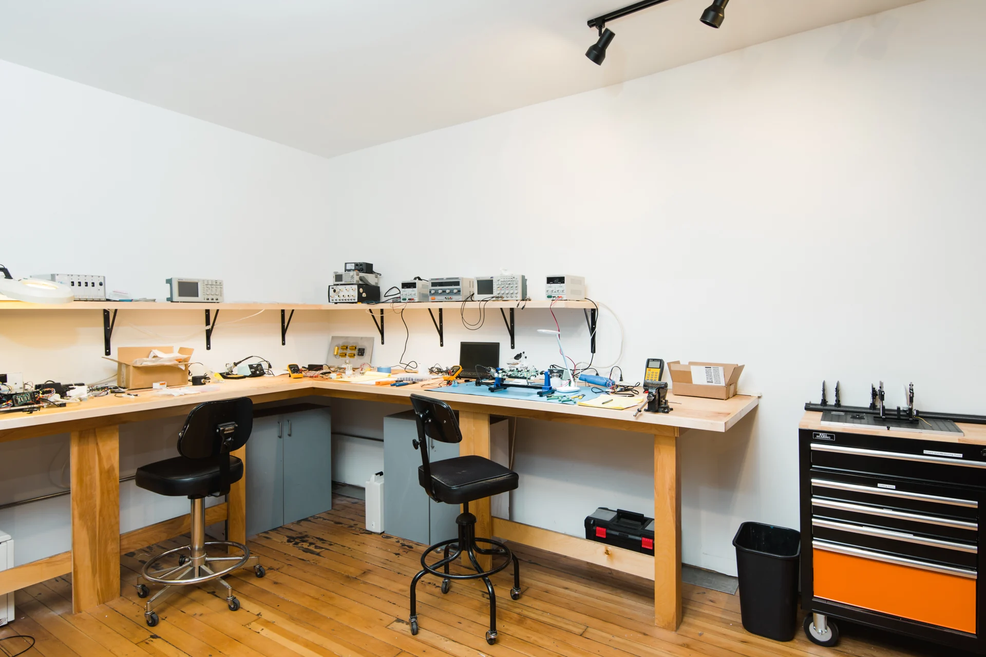 An electronics bench with test instruments, tools and stools.