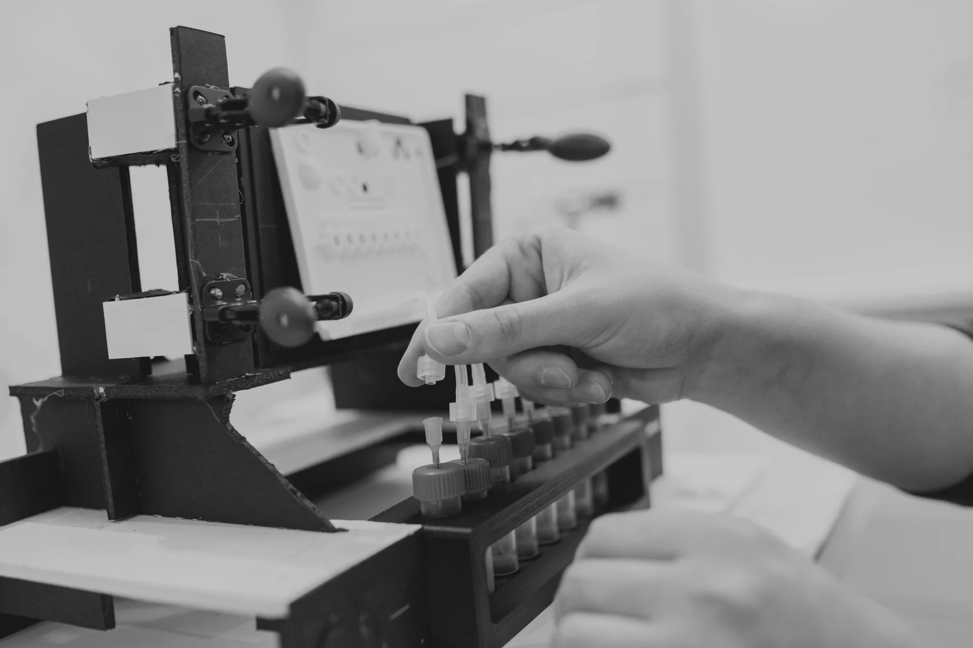 Hands adjusting tubing in an engineering test fixture.
